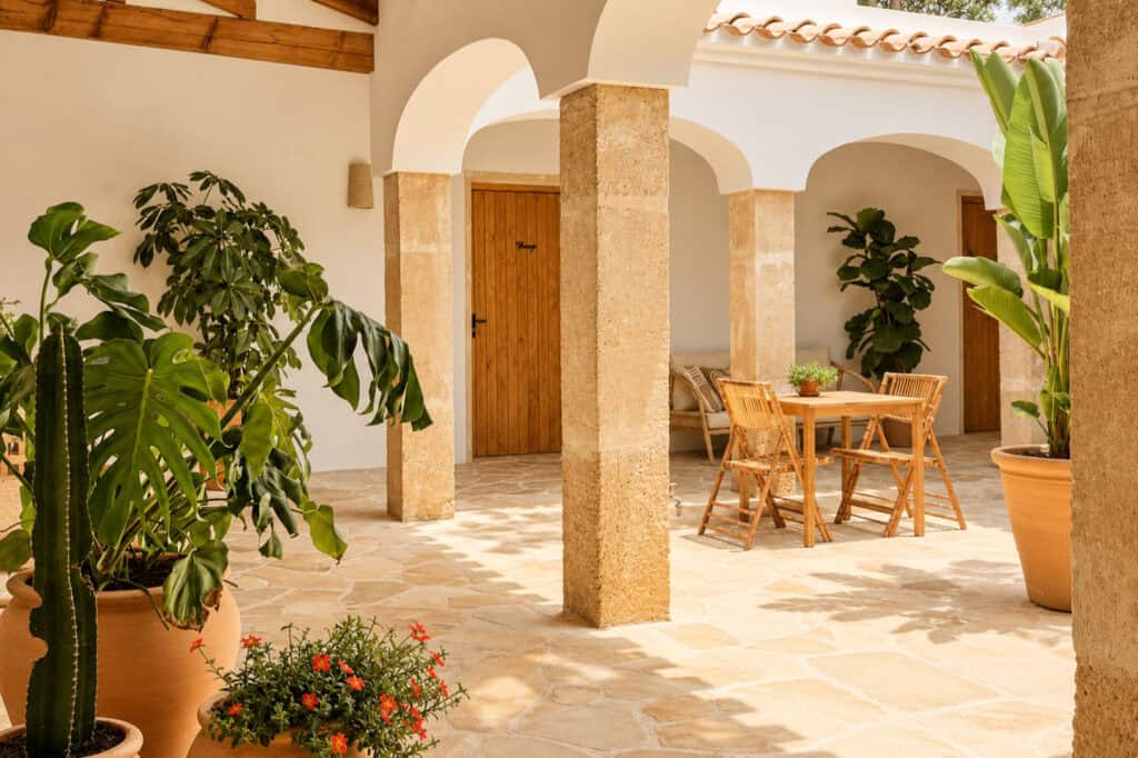 Patio met bogen, zuilen van toscasteen, terracotta potten en een zitje
